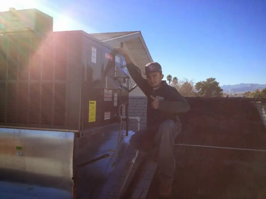 HVAC technician performing Air Duct Cleaning on a rooftop unit in Upper Darby